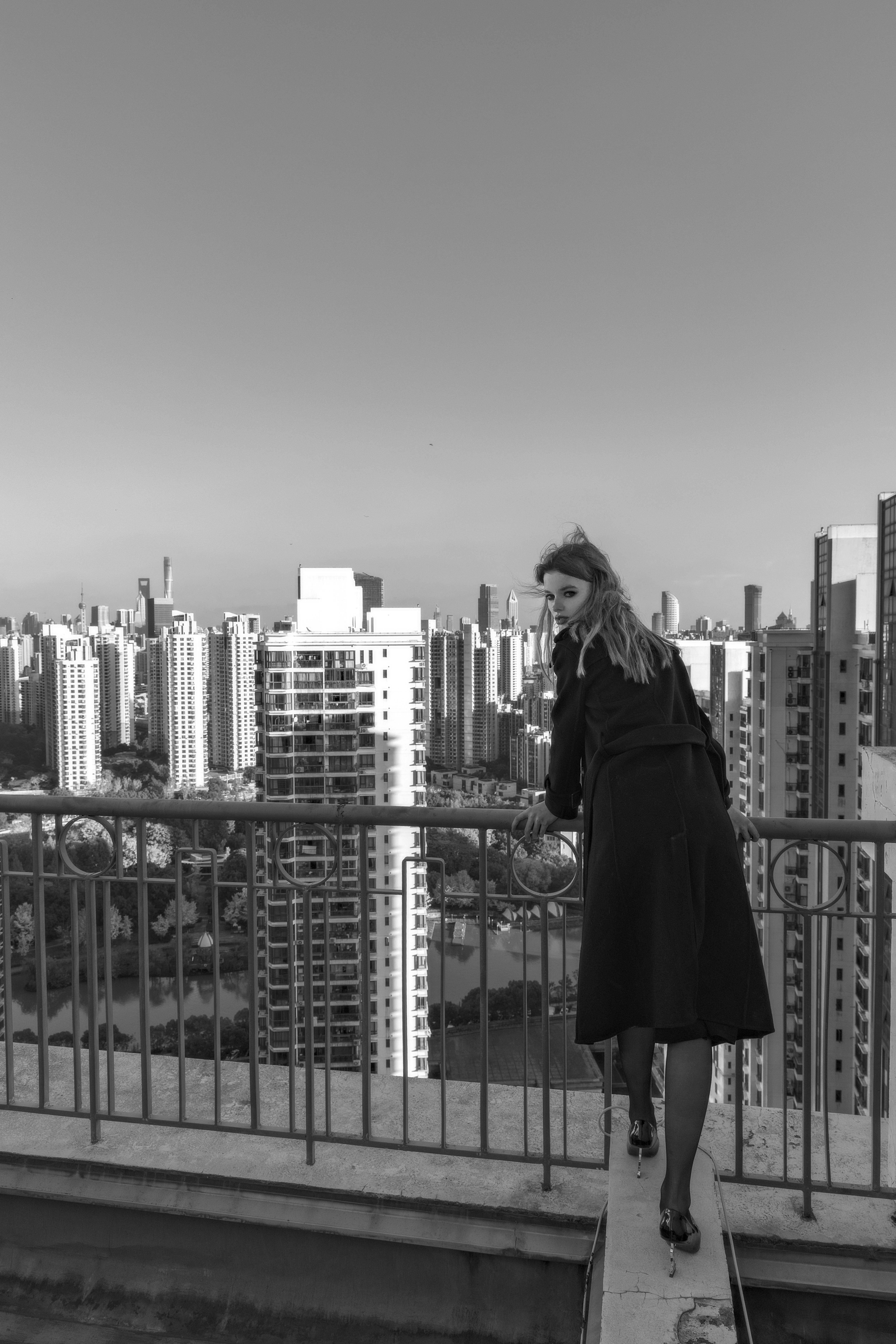 a woman in a black coat is standing on a balcony
