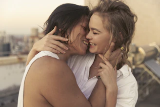 two young women embracing each other on a rooftop