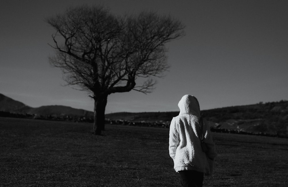 a person standing in a field next to a tree