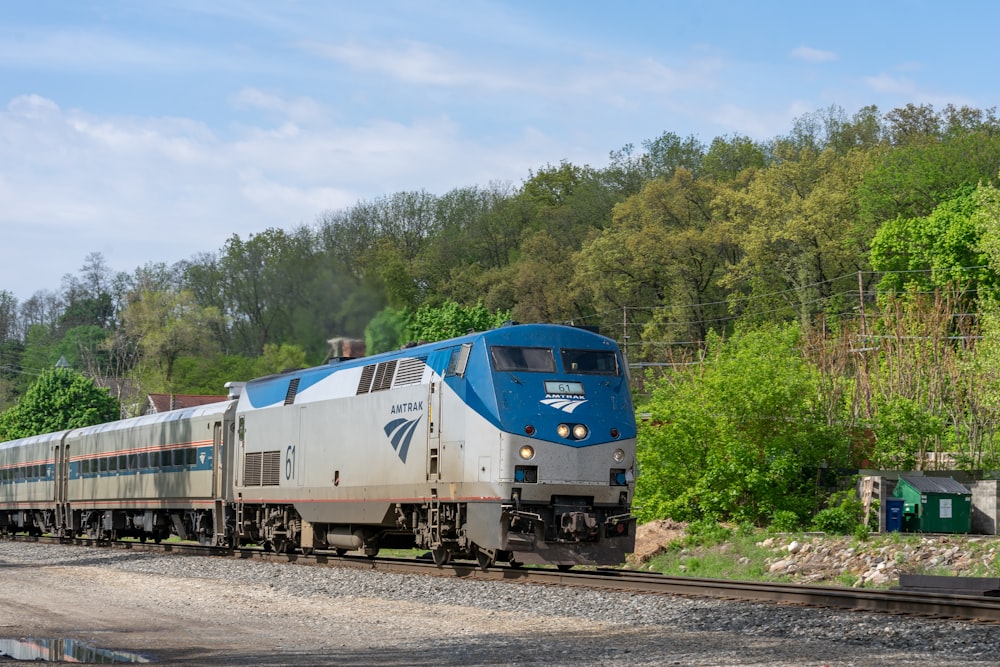 a blue and white train traveling down train tracks