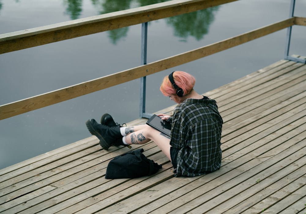a person sitting on a dock with a laptop