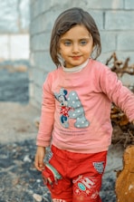 a little girl standing next to a tree stump