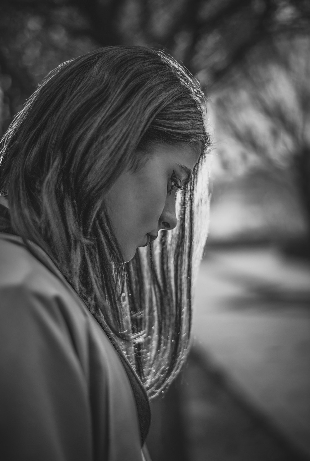 a woman with long hair standing in front of a tree