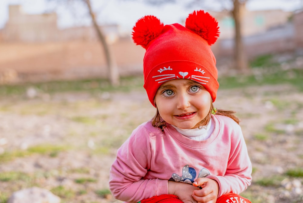 Una bambina che indossa un cappello rosso con due pom pom foto – Faccia  ragazza Immagine gratuita su Unsplash