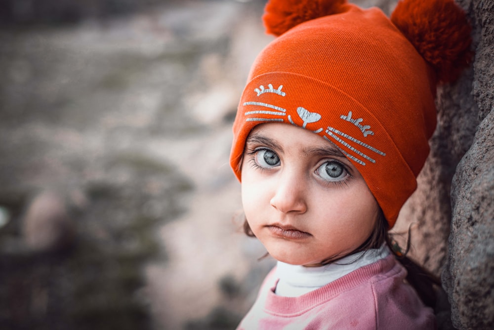 a little girl wearing a red hat with hearts on it