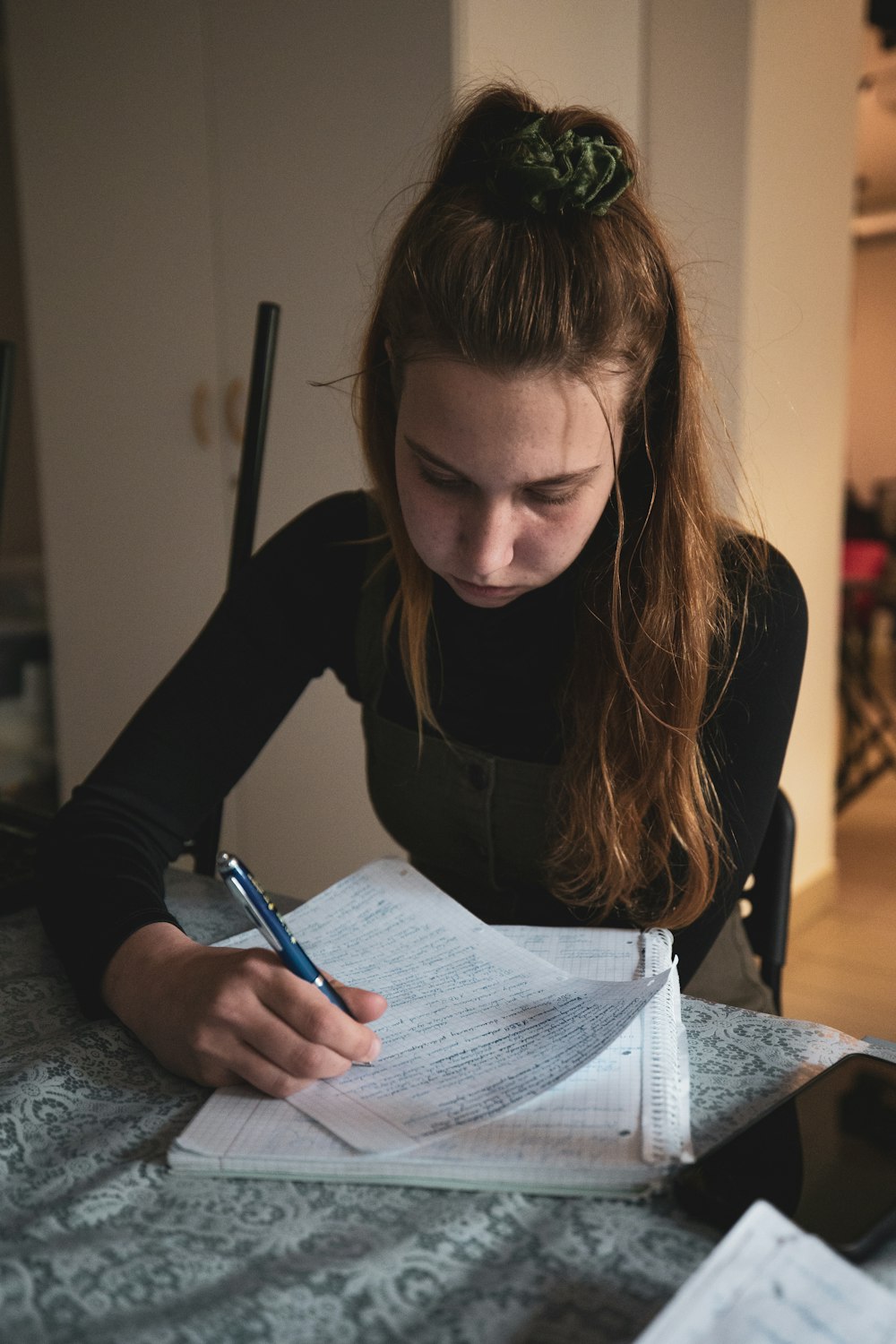 Una mujer sentada en una mesa escribiendo en un pedazo de papel