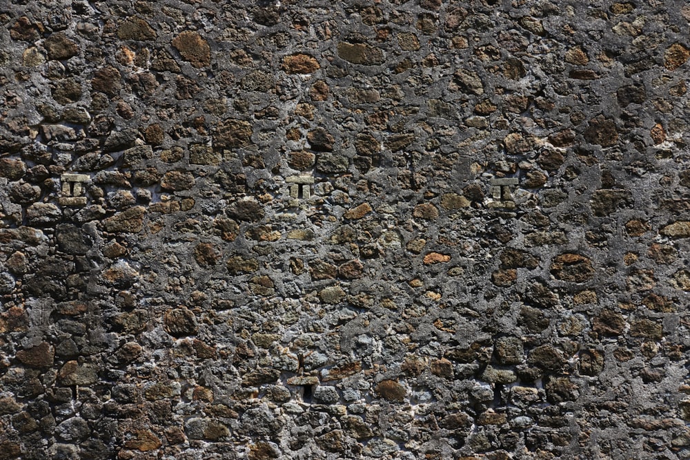 a close up of a stone wall with a clock on it