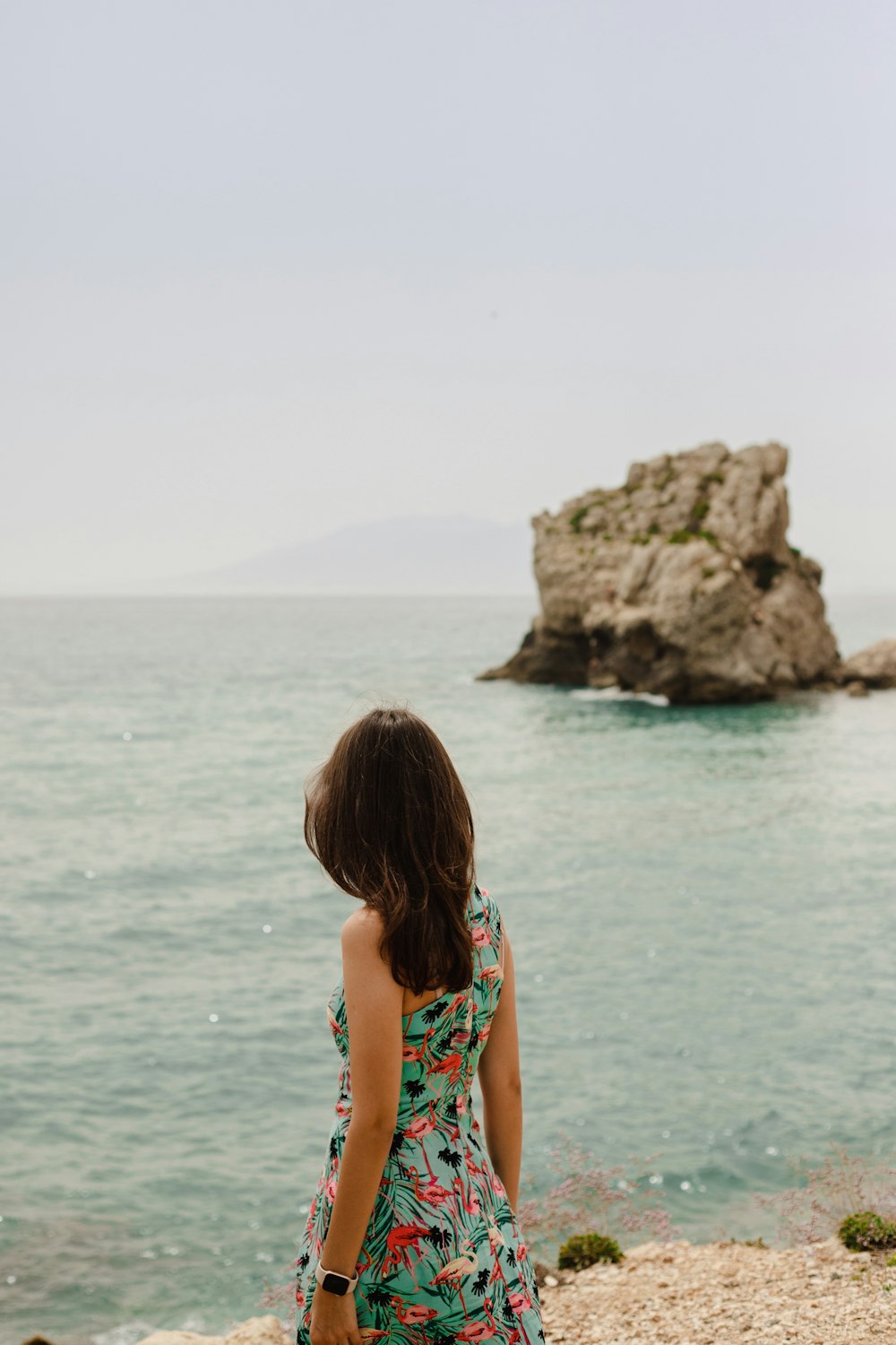 a woman standing on a beach looking out at the ocean