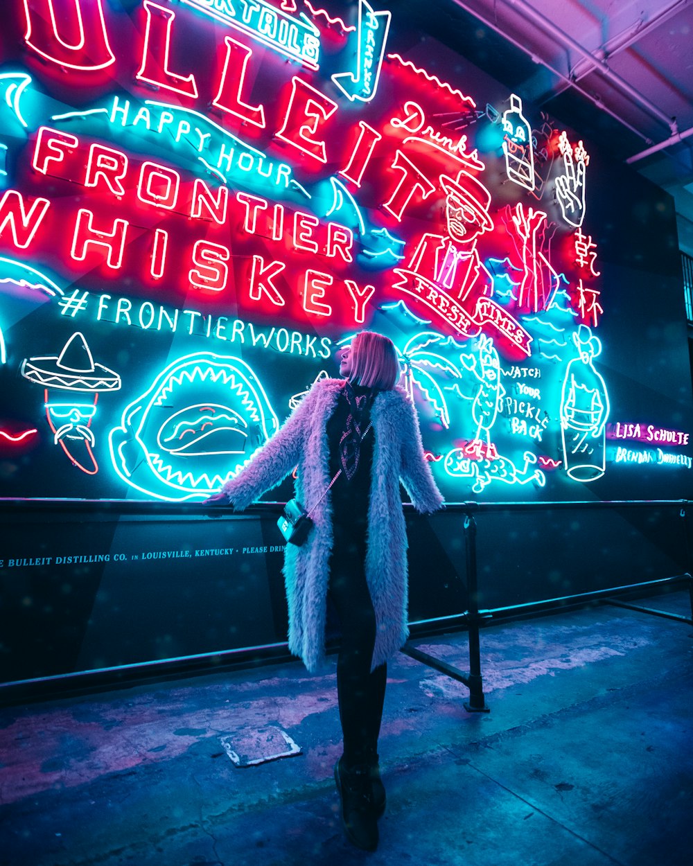 Una donna in piedi davanti a un'insegna al neon