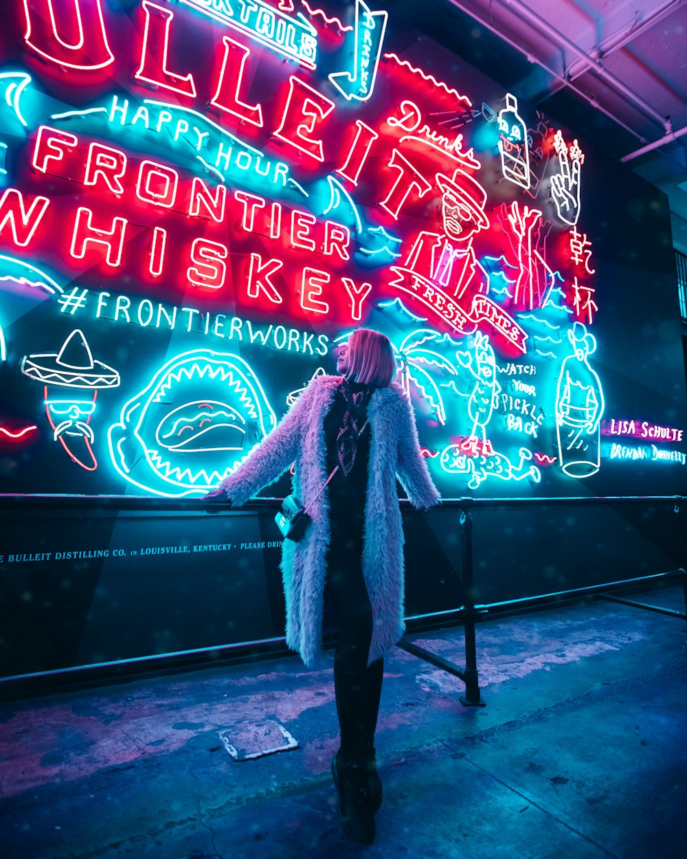 a woman standing in front of a neon sign