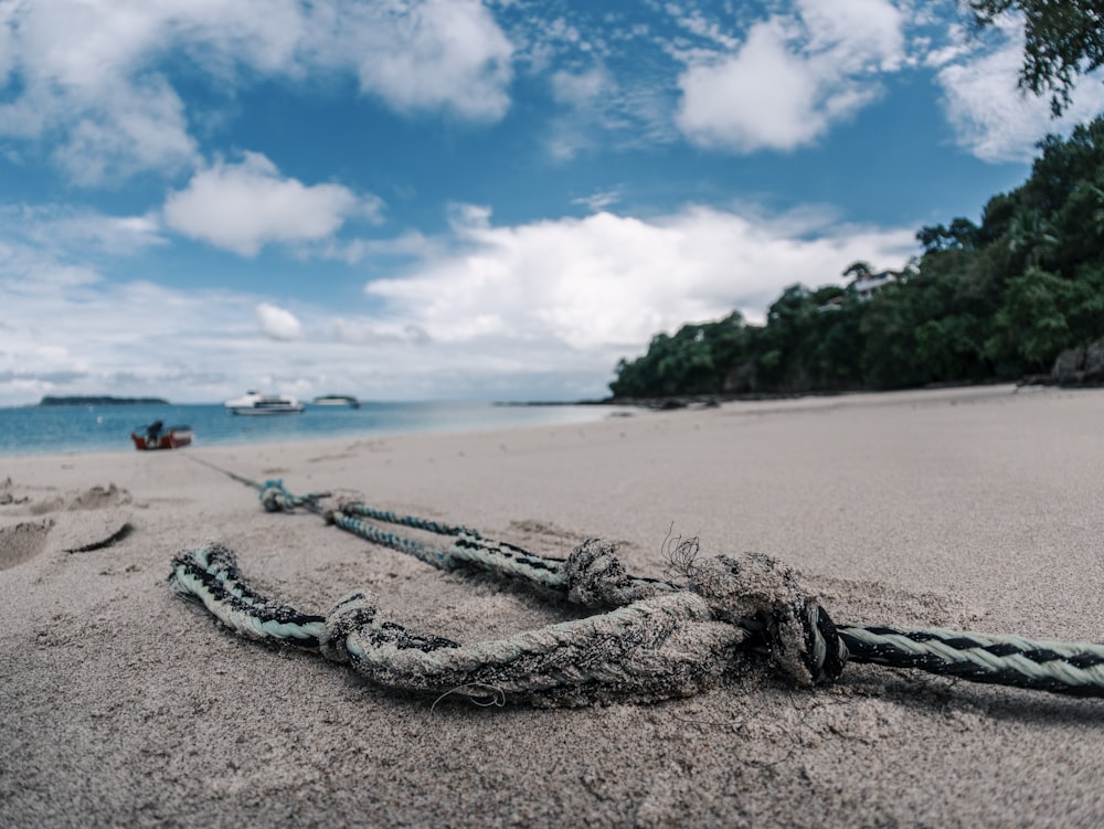 a rope on a beach with a boat in the background