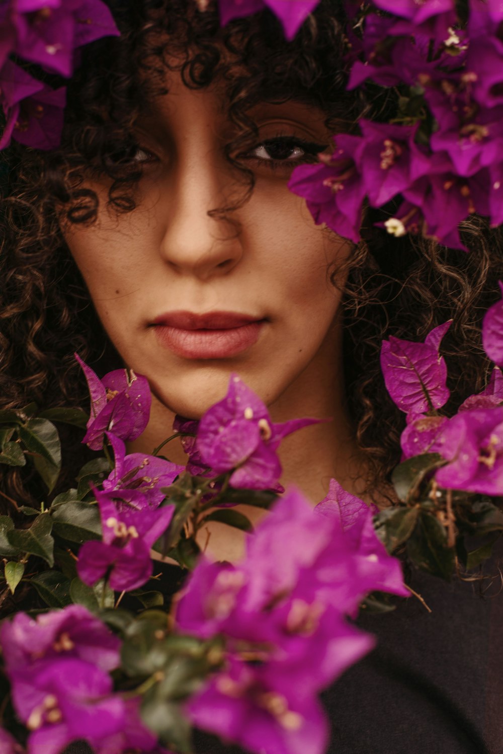 a woman with curly hair and purple flowers on her head