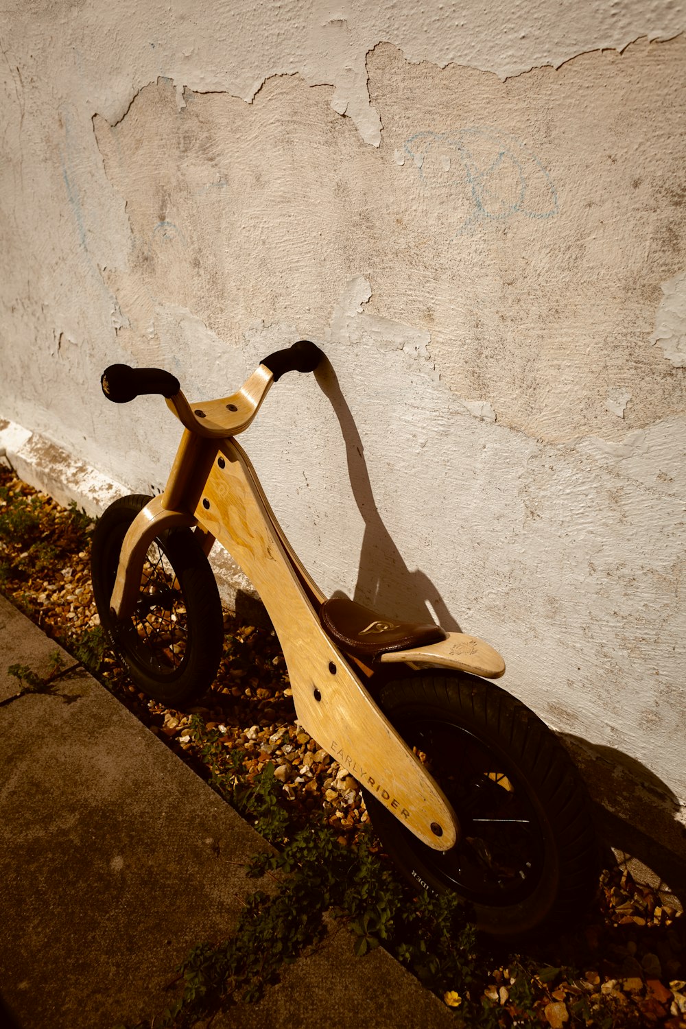 a wooden scooter leaning against a white wall