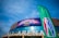 Kigali Arena with a large banner advertising a basketball event featuring several players, accompanied by a green flag displaying a basketball-themed logo. The sky is clear and blue, enhancing the vibrant setting.