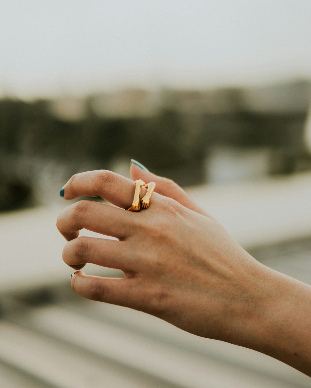 a woman's hand holding onto a gold ring