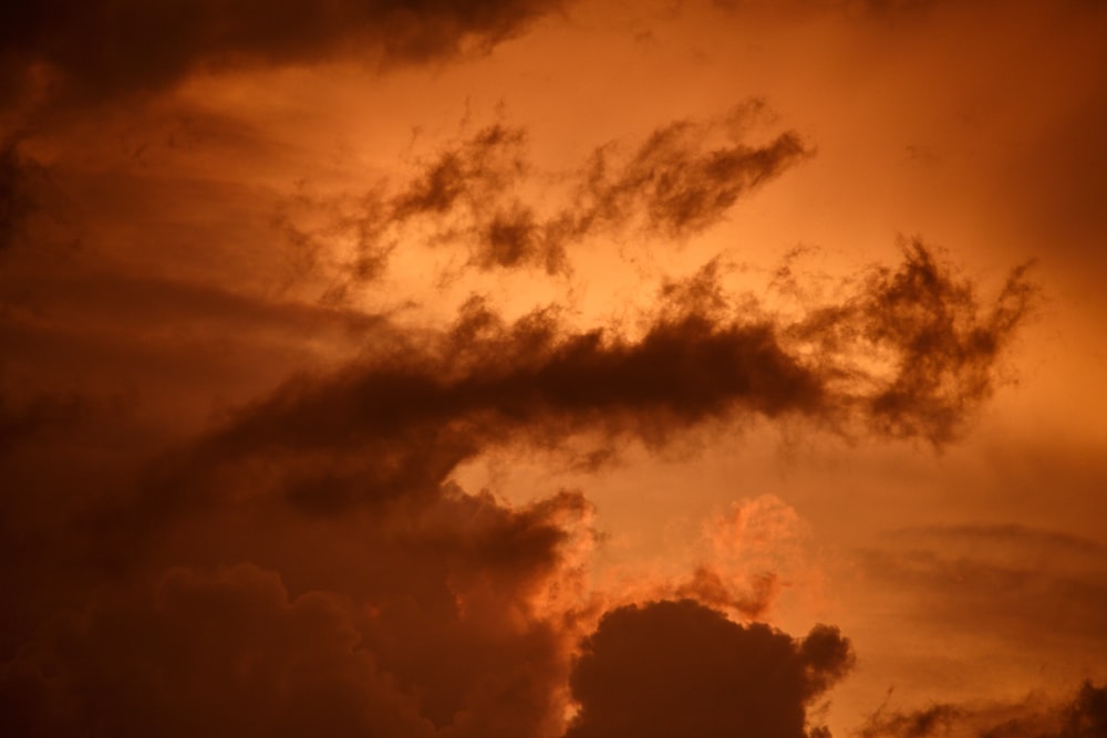 a plane flying through a cloudy sky at sunset