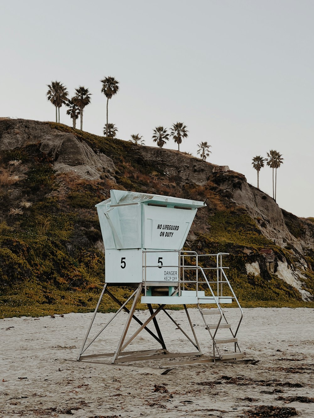 a lifeguard stand on the beach with palm trees in the background