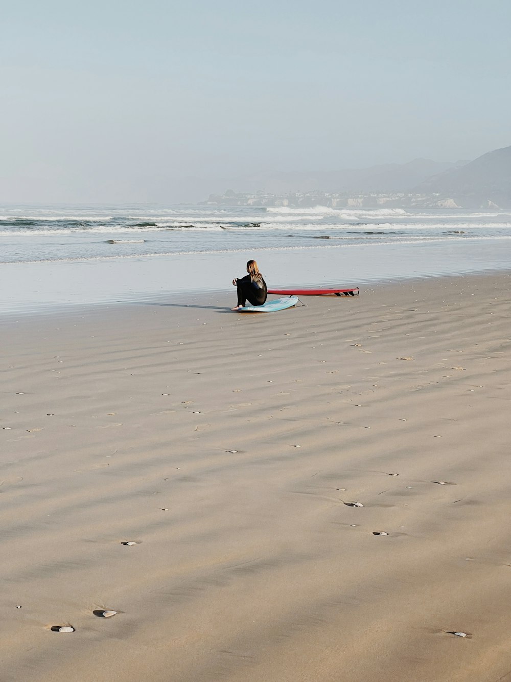 a person sitting on a surfboard on a beach
