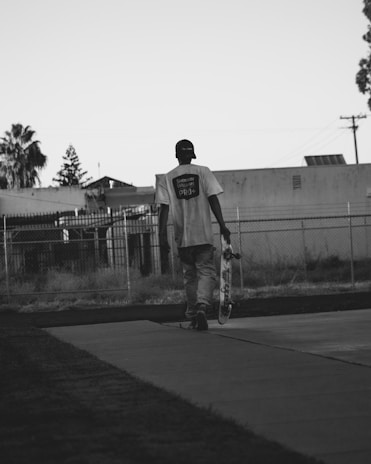 Close-up of hands holding a skateboard on a city sidewalk.