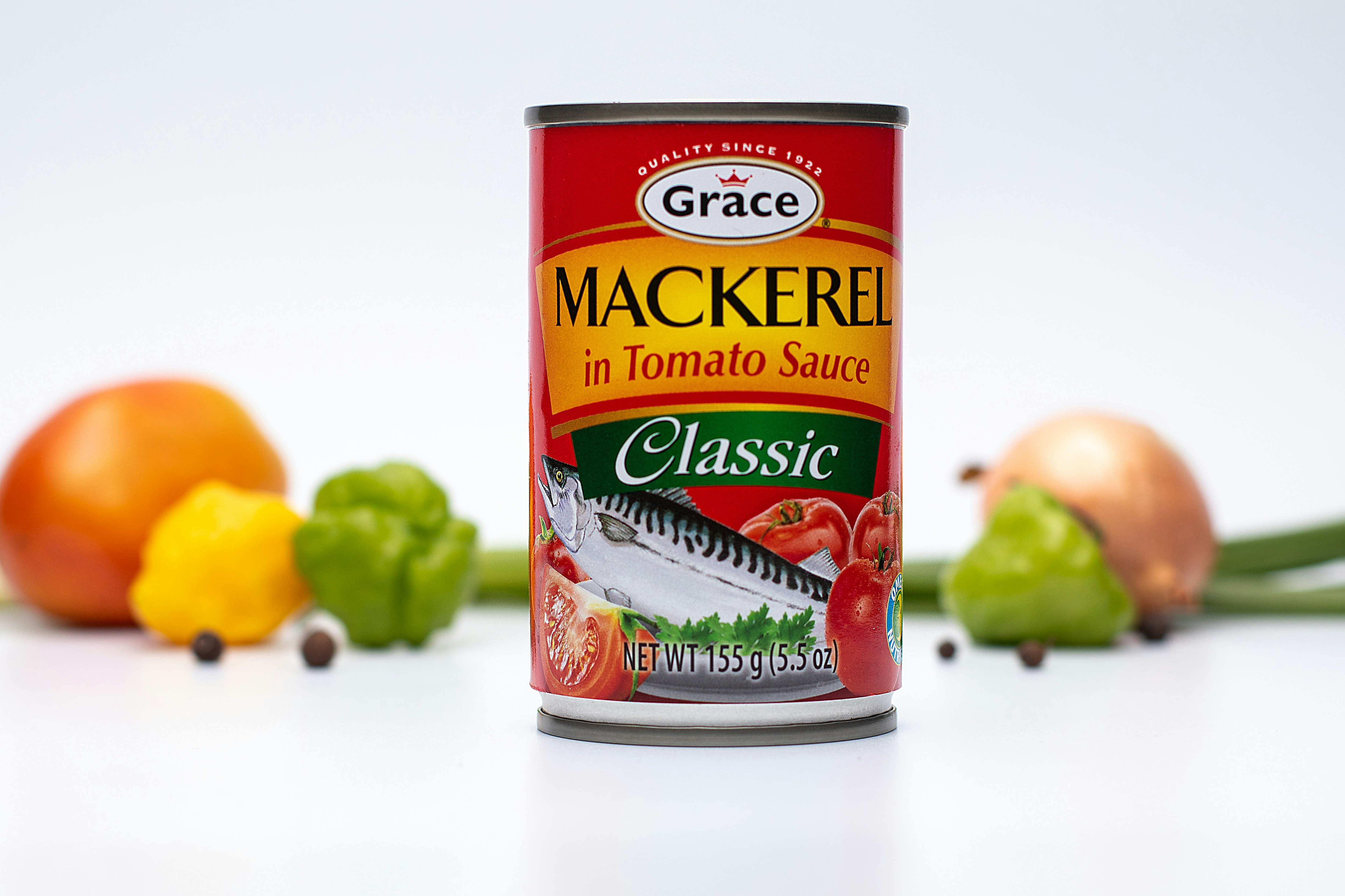 A can of Grace Kenedy's Mackerel (Grace Makerel) in Tomato Sauce on a white background with fresh seasonings