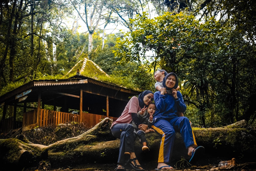 a group of people sitting on top of a fallen tree