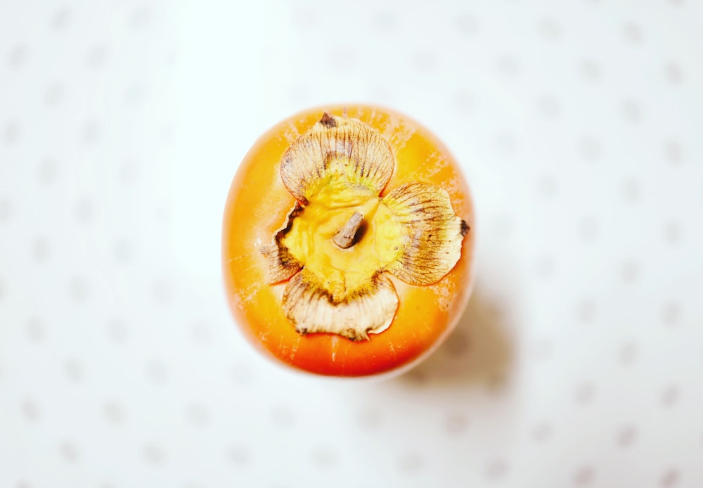 a close up of an orange with a flower on it