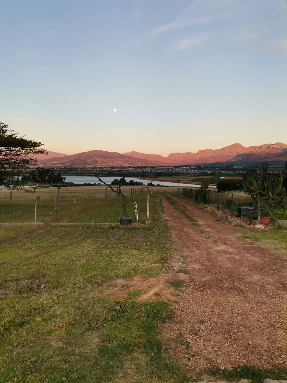 uma estrada de terra em um campo com montanhas ao fundo