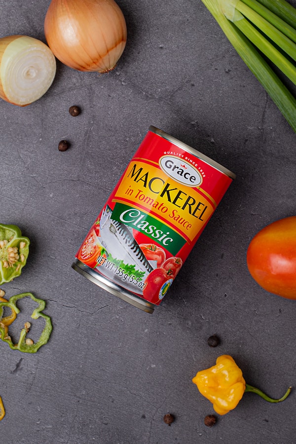 A can of canned food next to some vegetables