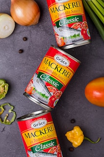 three cans of mackerel on a table next to some vegetables