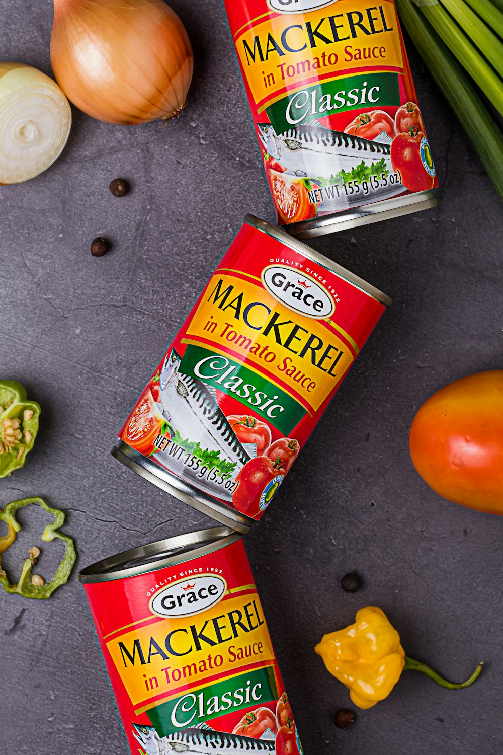 three cans of mackerel on a table next to some vegetables