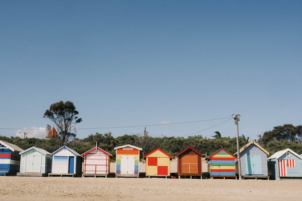 a row of colorful beach huts sitting on top of a sandy beach