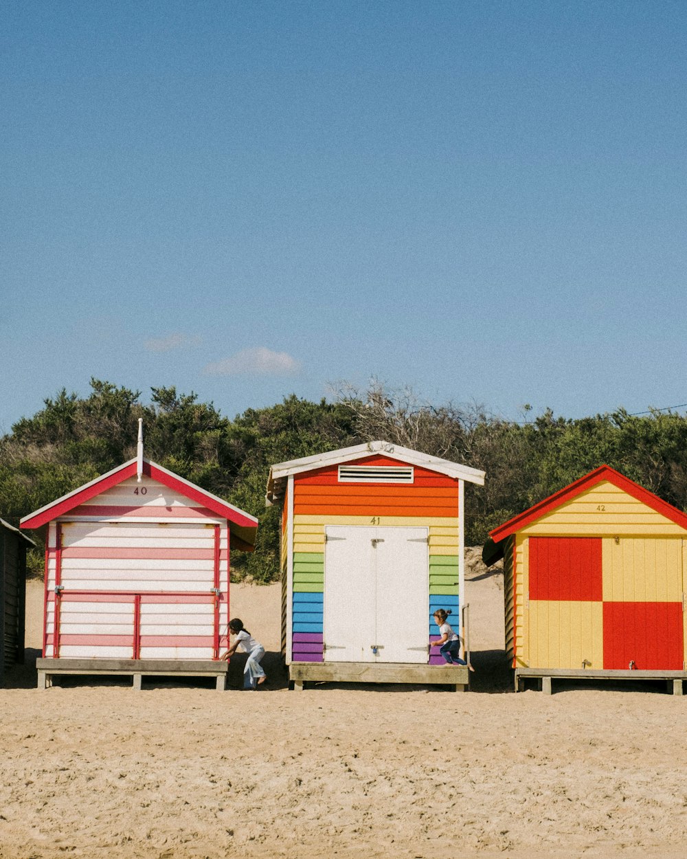 Una hilera de coloridas cabañas de playa sentadas en la parte superior de una playa de arena