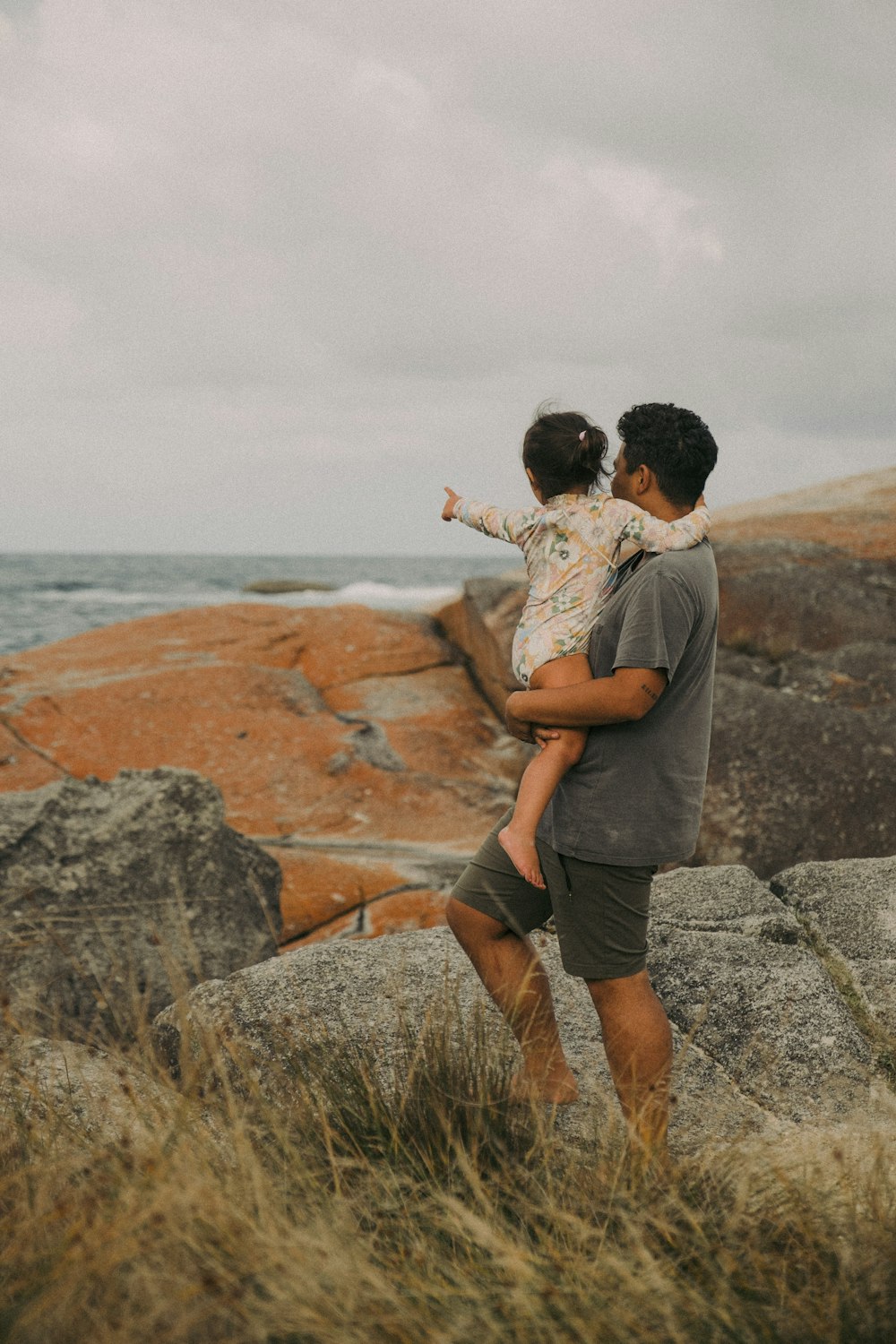 a man holding a little girl on top of a rock