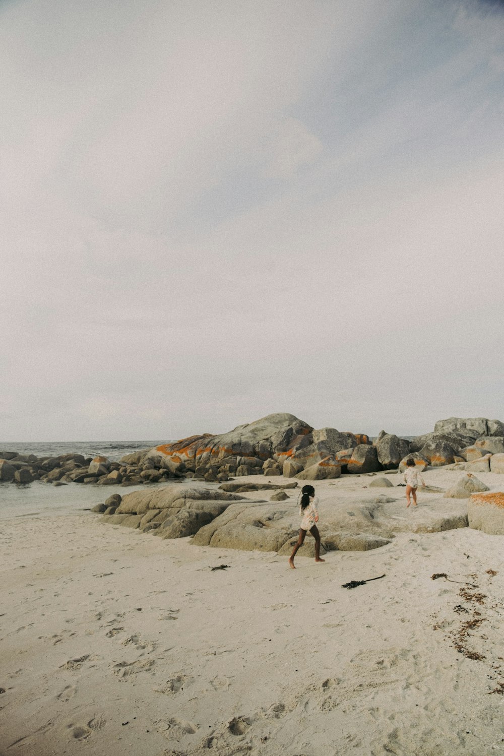 a couple of people standing on top of a sandy beach