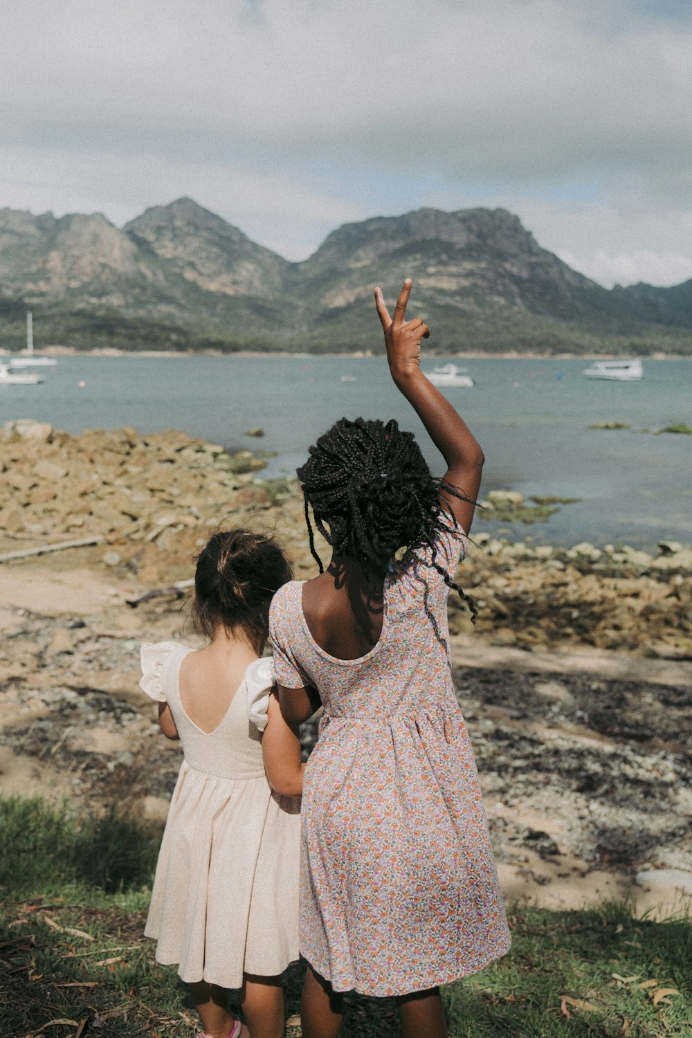 two little girls standing next to each other near a body of water