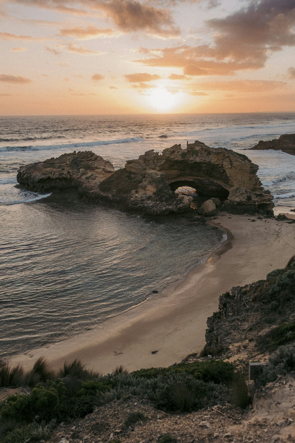 the sun is setting over the water at the beach