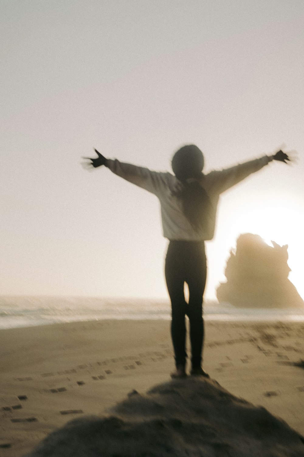 a person standing on a beach with their arms outstretched