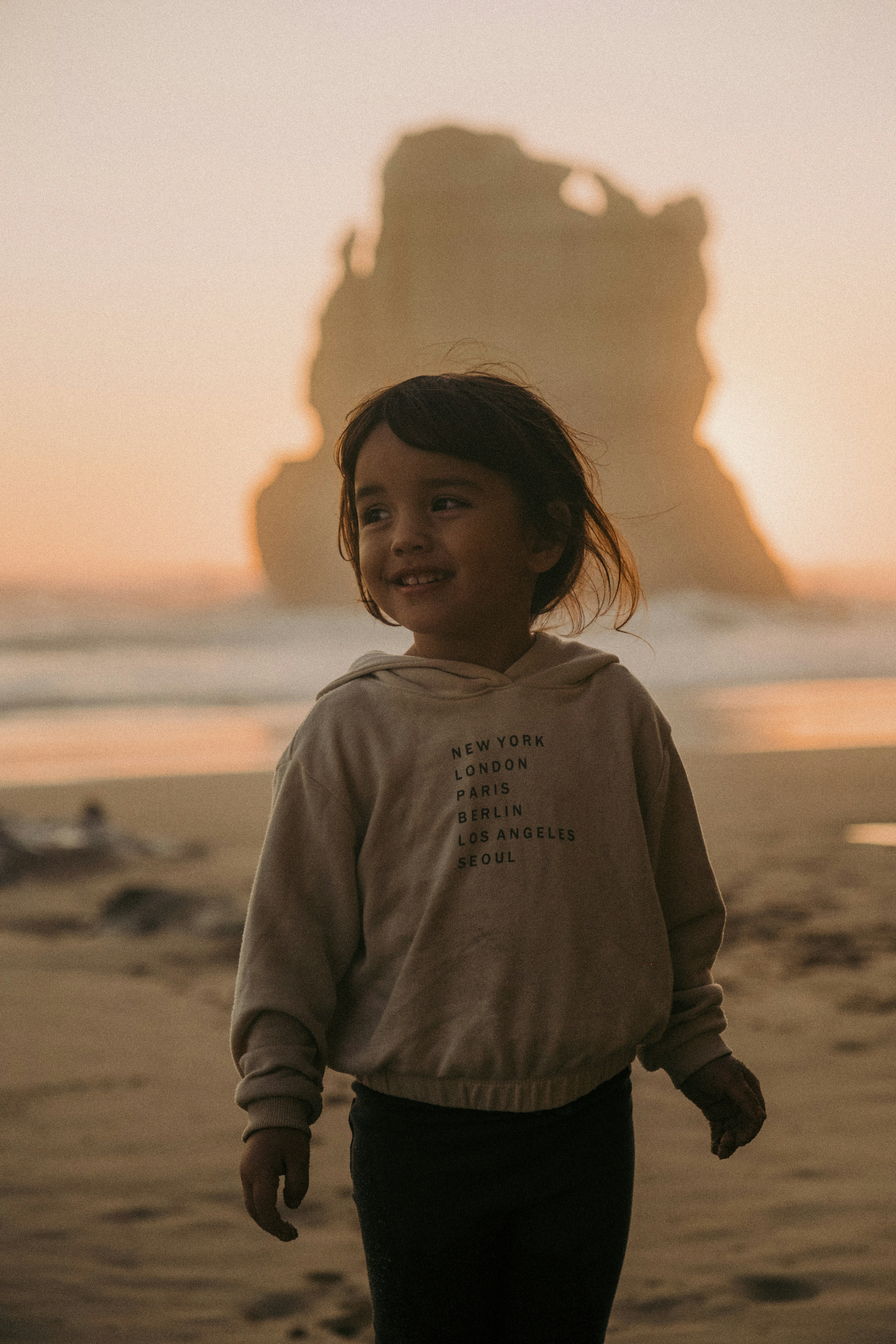 Ein kleines Mädchen steht auf einem Sandstrand