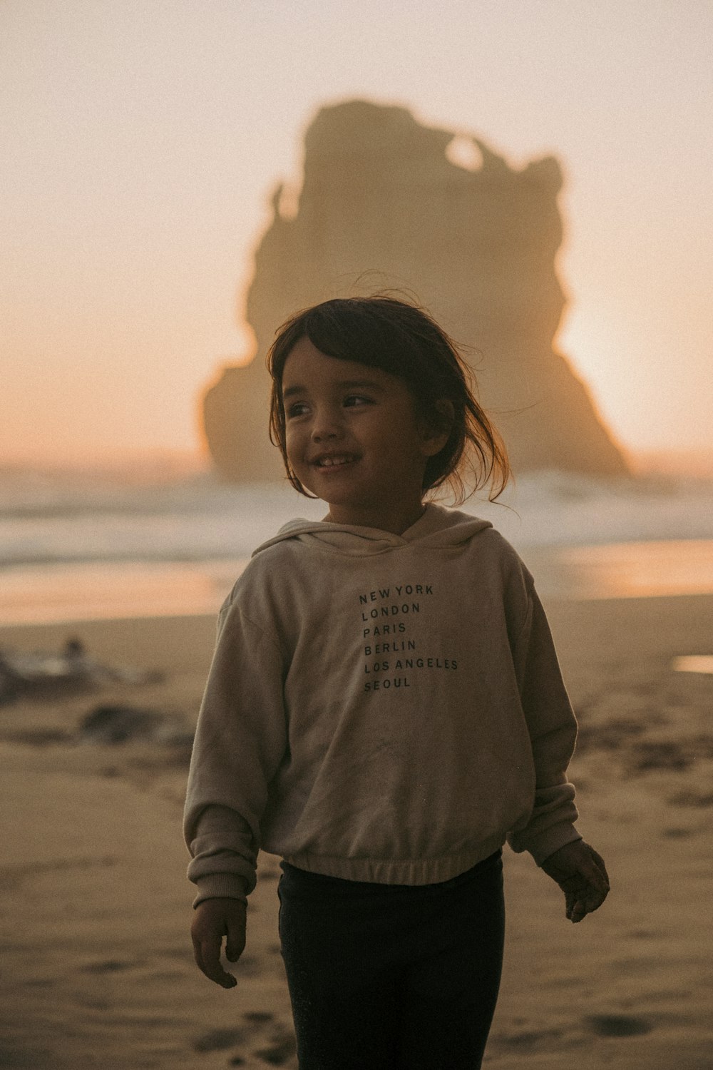 a little girl standing on top of a sandy beach