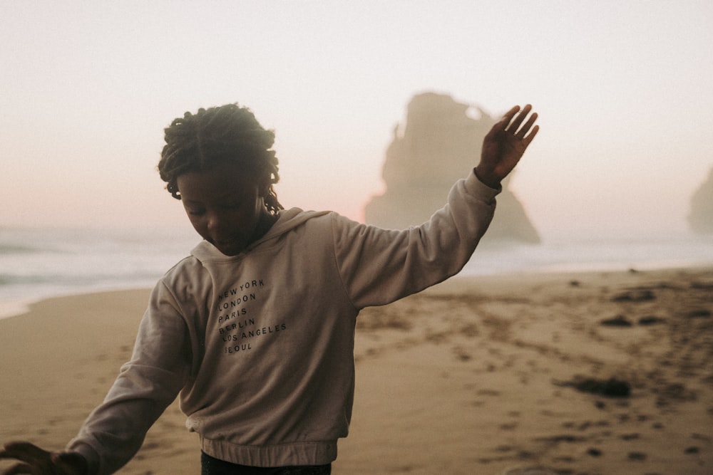 a young man standing on top of a sandy beach