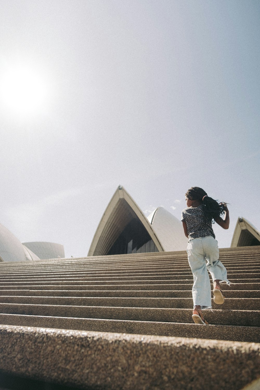 a woman walking up some steps in front of a building