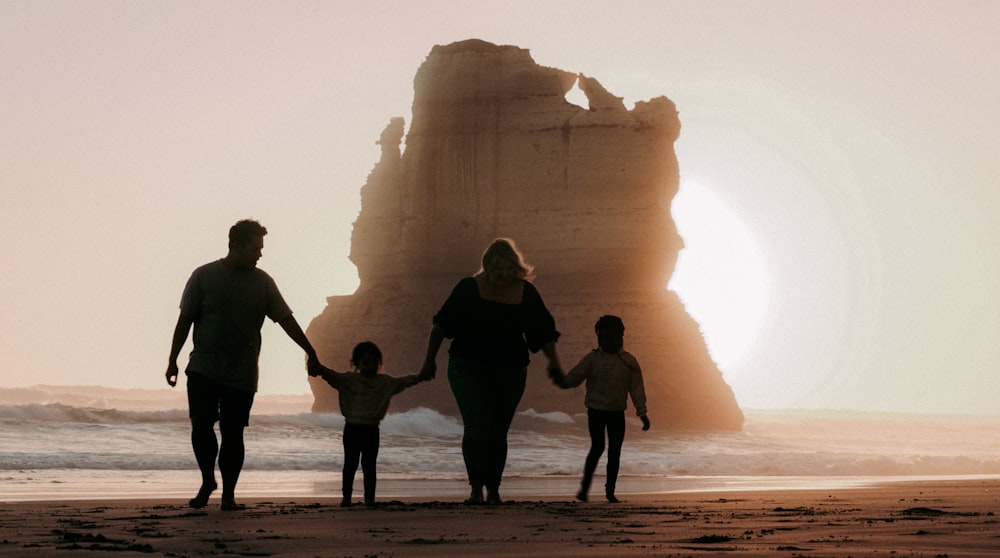 a family walking on the beach at sunset