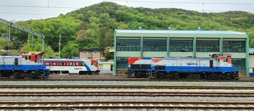 a blue and white train traveling past a train station