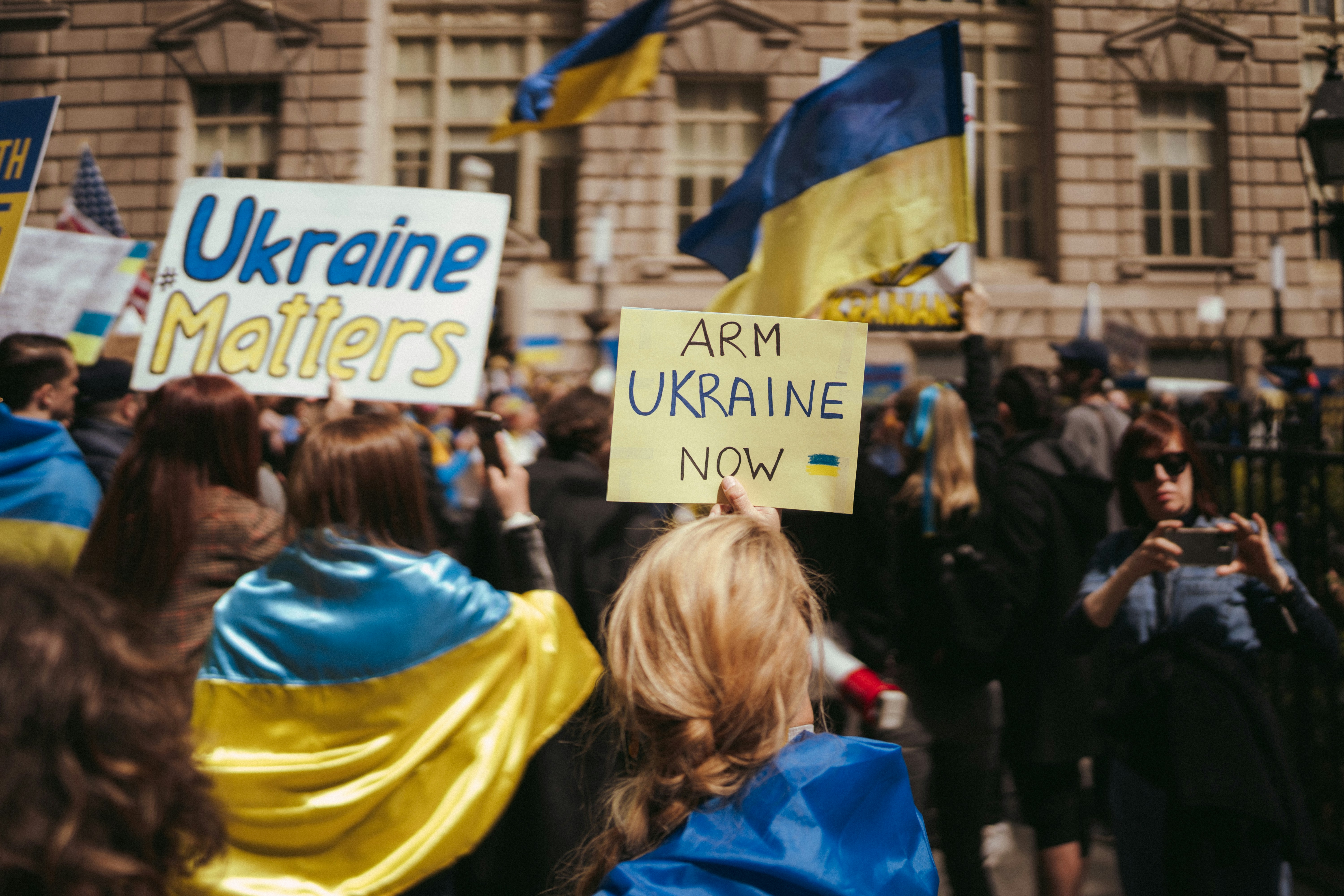 a group of people holding up signs in front of a building 