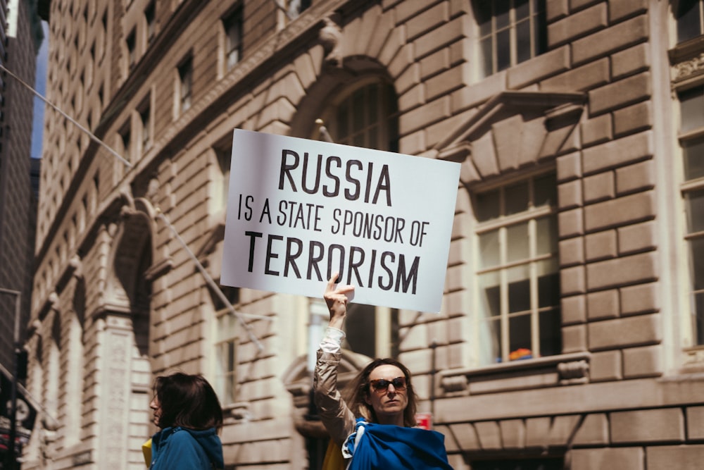 a woman holding a sign in front of a building