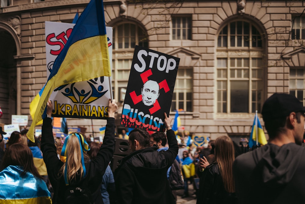 a group of people holding up signs in front of a building