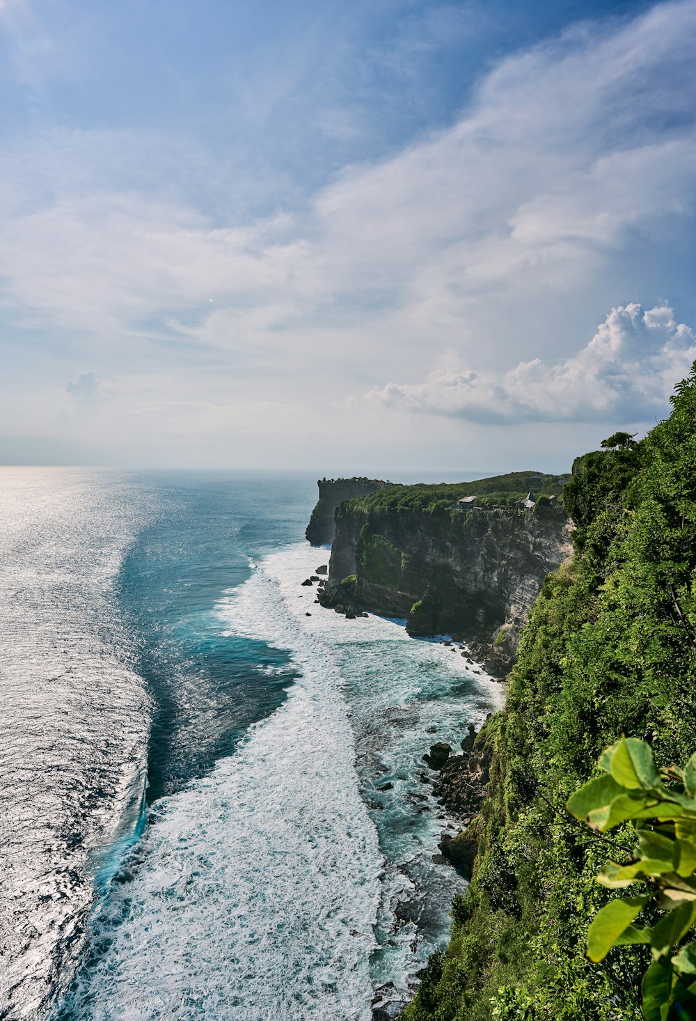 a large body of water next to a lush green hillside