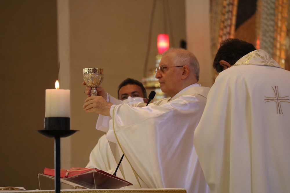 a priest holding a lit candle in a church