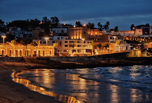 Night shot of a luxury beachfront complex illuminated with warm lights.