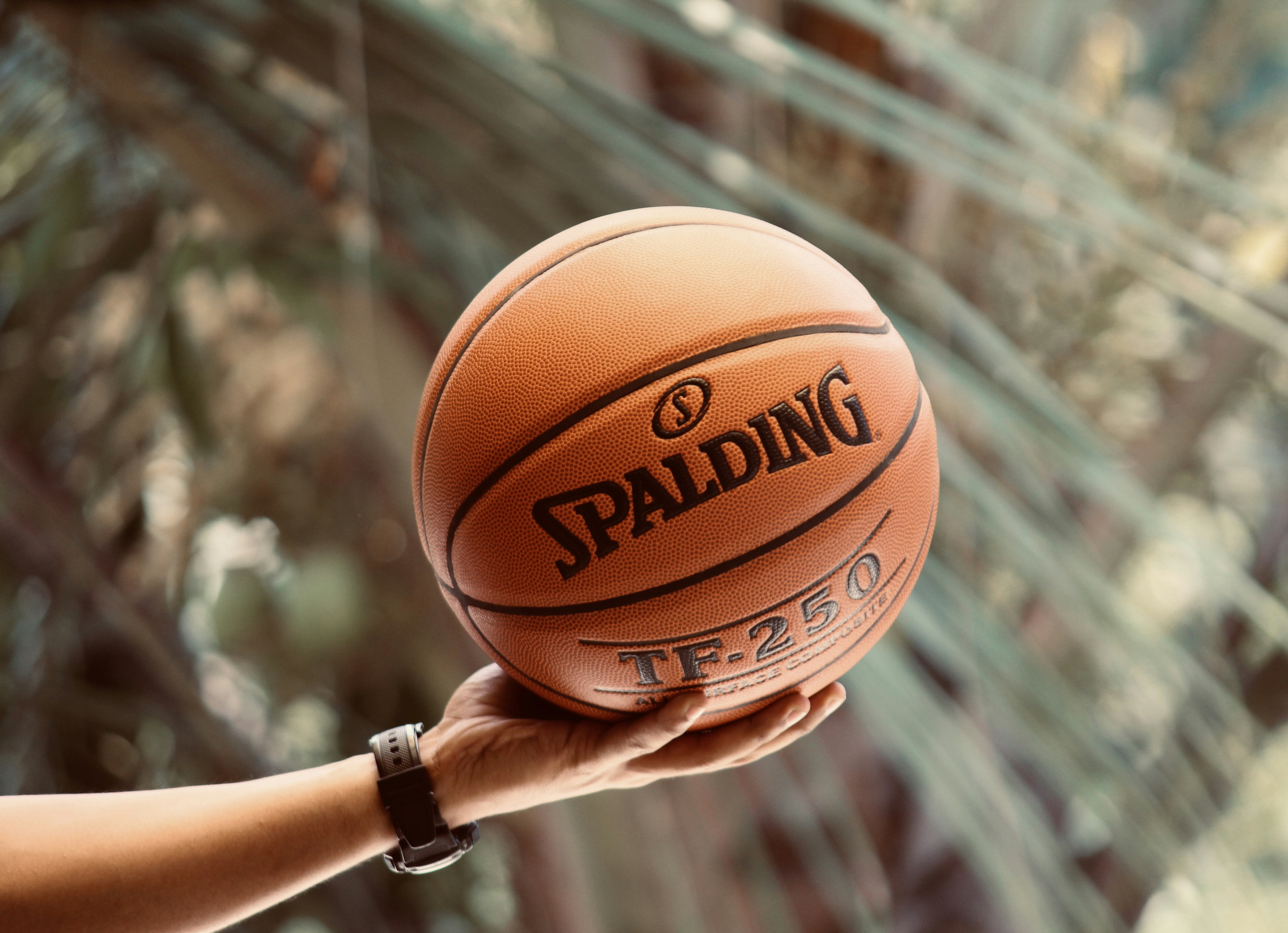 Man holding a Spalding TF -250 basketball.